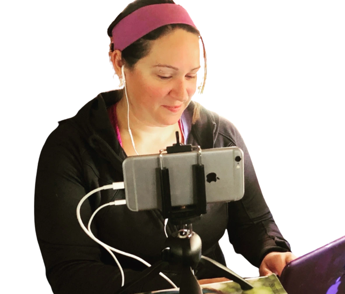 Lezlie working with earbuds in, a phone on a tripod, and a laptop
